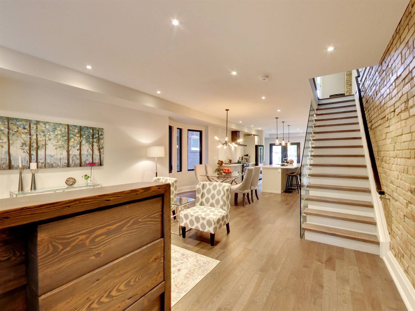 Open-concept living space with brick wall and staircase